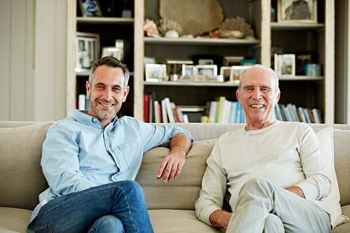 Portrait of happy father and son sitting on sofa at home