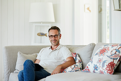 Portrait of confident man with digital tablet sitting on sofa at home
