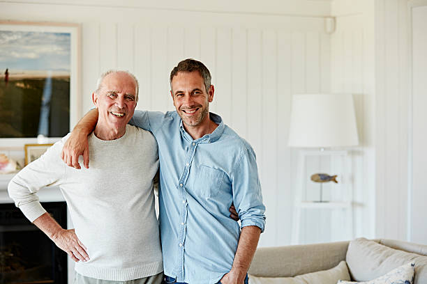 portrait of smiling father and son at home - senior adult fotografías e imágenes de stock