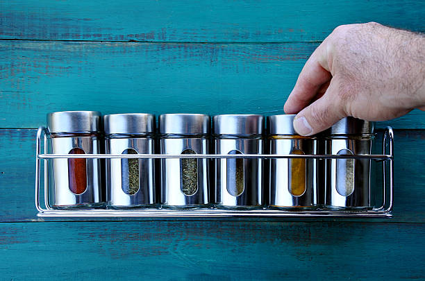 Chef hand returning spice into a spice rack Chef hand returning spice into a spice rack. Food background. copy space spice rack stock pictures, royalty-free photos & images