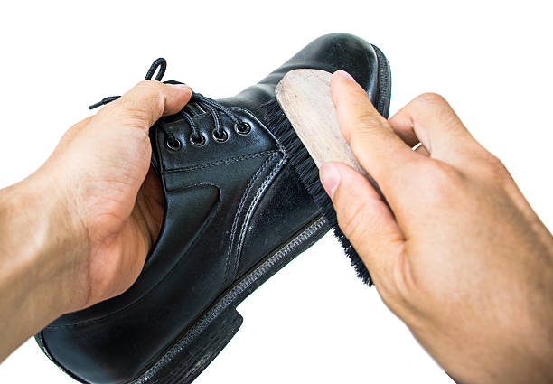 istock hand with brush cleaning black leather shoe 594908286