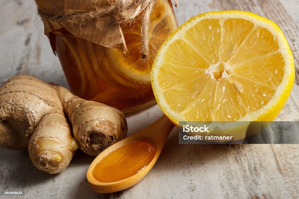 Fresh lemon, honey and ginger on wooden table, healthy nutrition Lemon with honey in glass jar, honey on wooden spoon and ginger on old rustic board, concept of healthy food, nutrition and strengthening immunity Alternative Therapy Stock Photo