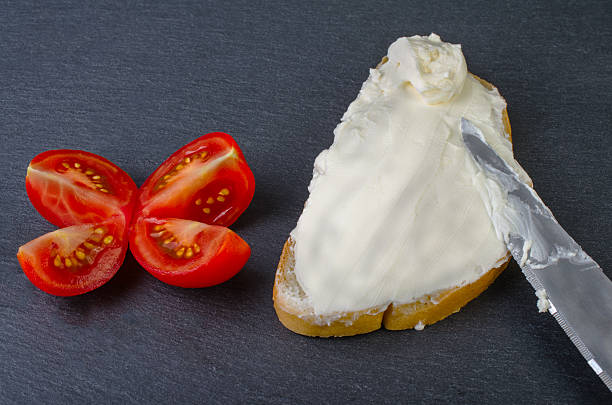 istock Bread with butter knife and tomato on a dark background. 594912010