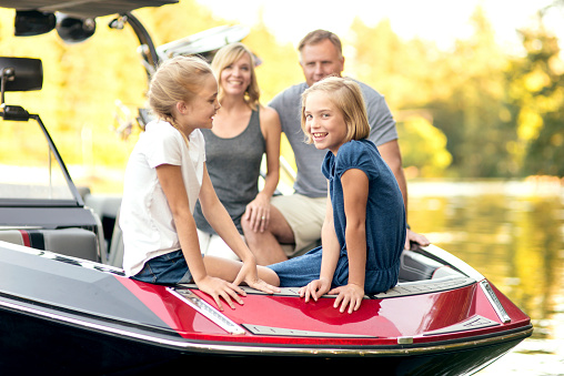 Beautiful family sitting in the front of their competition ski boat getting ready for a day on the water