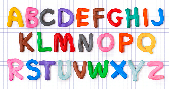 Handmade plasticine alphabet with shadow on notebook sheet. English colorful letters of modelling clay.