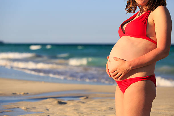 istock Happy pregnant woman at beach 594918336