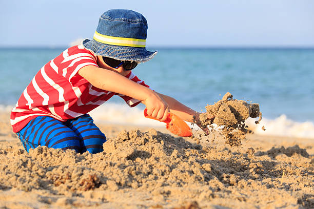 istock little boy play with sand on beach 594921472