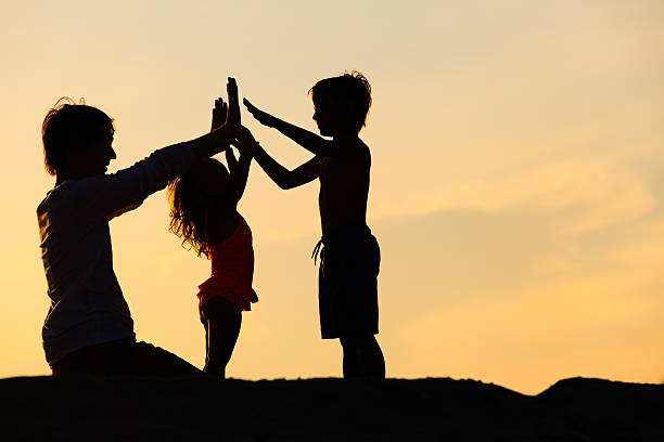 istock father with son and daughter silhouettes play at sunset 594922664