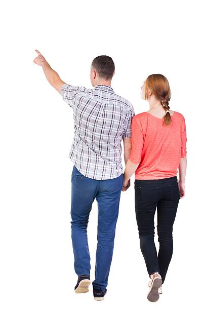 istock Back view of walking young couple (man and woman) pointing. 594929536