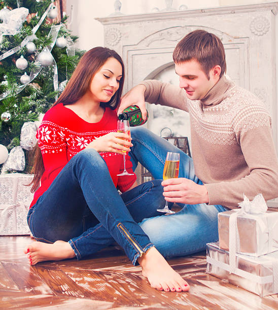 istock Young smiling couple drinking champagne by the Cristmas tree 594932220