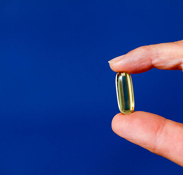 istock Cod liver oil omega 3 gel capsule between fingers 594932554