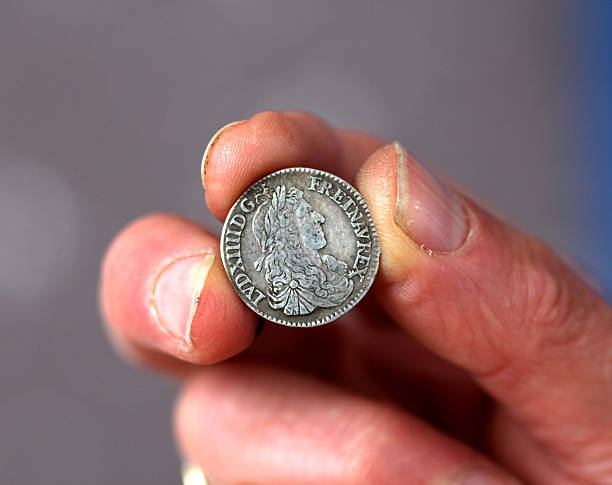 istock Fingers hold old coin from France 594934270