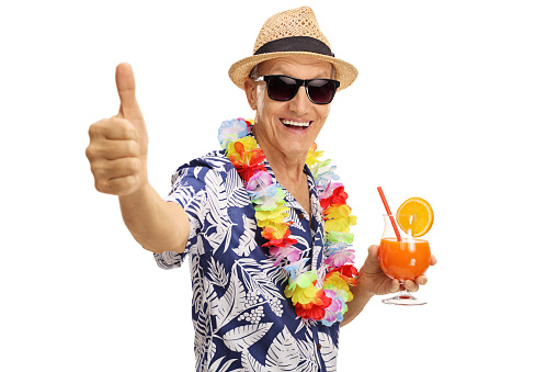 Cheerful senior tourist holding a cocktail and giving a thumb up isolated on white background