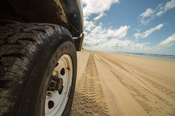4x4 trucks wheels' footprints at Fraser island beach sand. Ocean in background. Queensland, Australia.