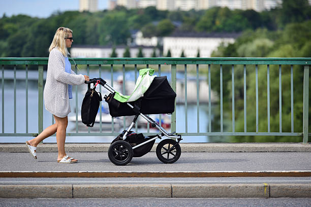 Stockholm, Sweden - August 22, 2016: Mother and child in stroller, on street/ bridge, Stockholm view in background, Karlberg. 
