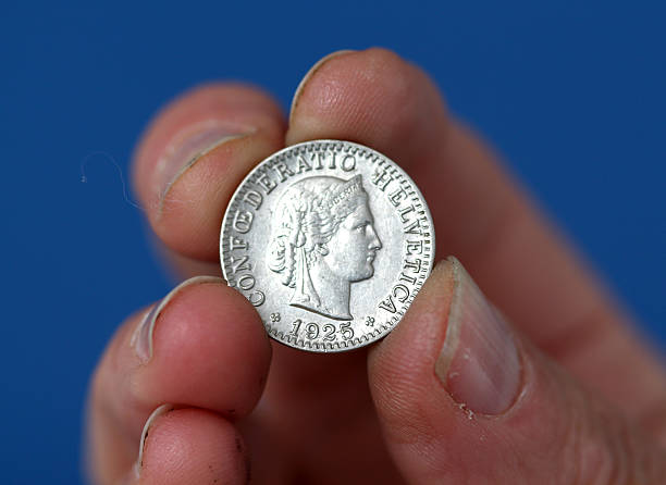 istock Fingers hold old coin from switzerland 594938294