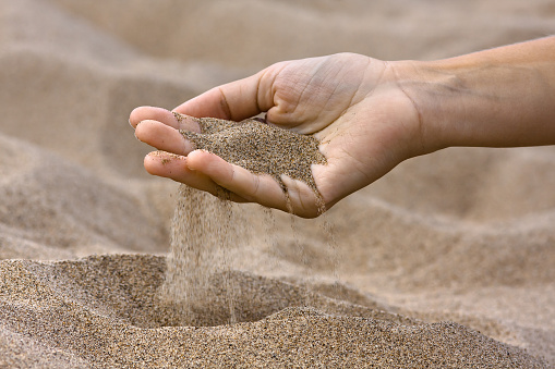 sand running through fingers in the beach