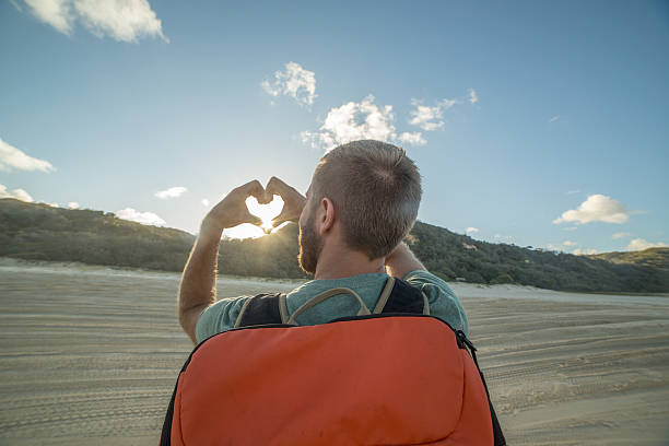 istock Traveler on beach at sunset makes heart shape finger frame 594949102