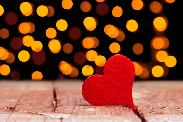 istock Red heart on wooden board against defocused lights 594949810
