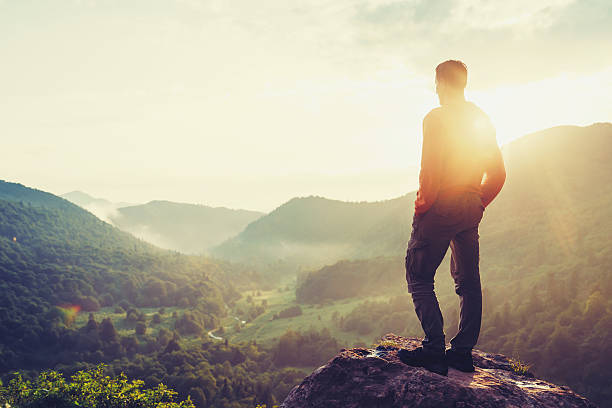 istock Traveler man standing in mountains at sunset 594951760