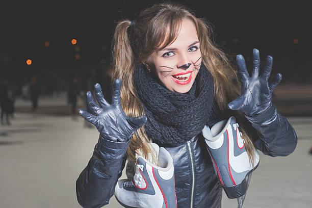 ハロウィンパーティー!猫の役割のような若い女性。猫のカーニバルマスク。 - ice skating outdoors playful playing ストックフォトと画像