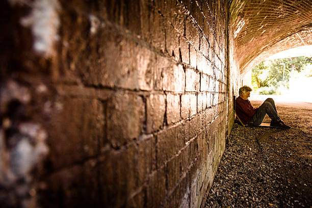 homeless adulta senior hombre sentado y cualquier en un túnel subterráneo - brick wall homelessness wall begging fotografías e imágenes de stock