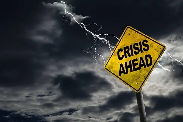 Crisis Ahead sign against a stormy background with lightning and copy space. Dirty and angled sign adds to the drama. Concept of political, financial, social, health crisis, etc.