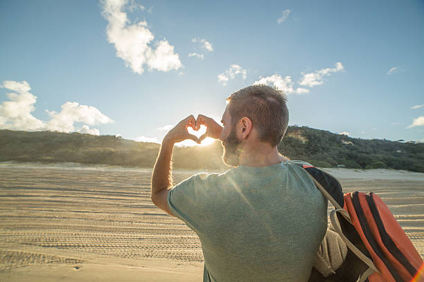istock Traveler on beach at sunset makes heart shape finger frame 595120062