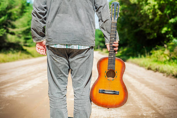 istock Man with guitar on rural road 595134154