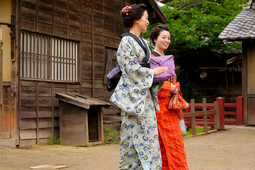 Two Japanese women walking on a dirt street in an Edo Period town. Photographed on location in Kyoto, Japan.