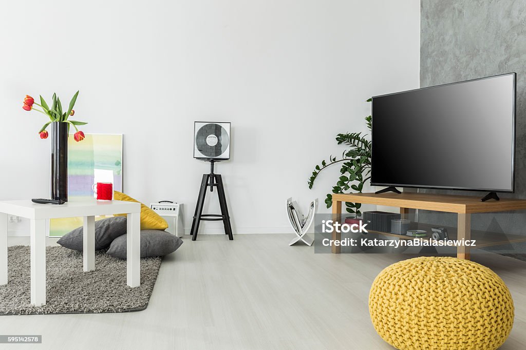 Airy interior for enthusiasts of good movies Modern living room with simple but trendy furniture and a tv set, arranged in grey and yellow Television Set Stock Photo