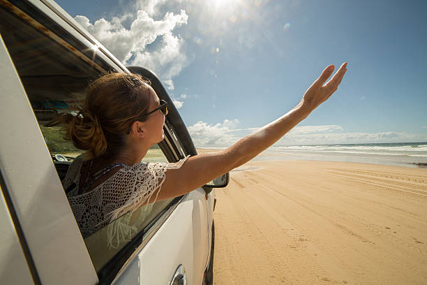 istock Young woman in a car driving on sandy beach 595149116
