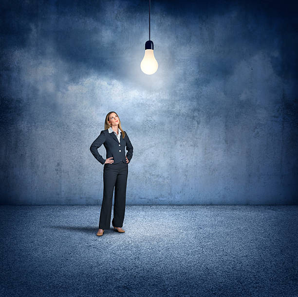 istock Businesswoman Standing While Looking Up At Lightbulb 595156408