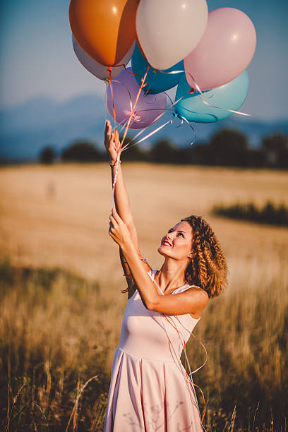 istock Woman with balloons in a wheat field 595158198