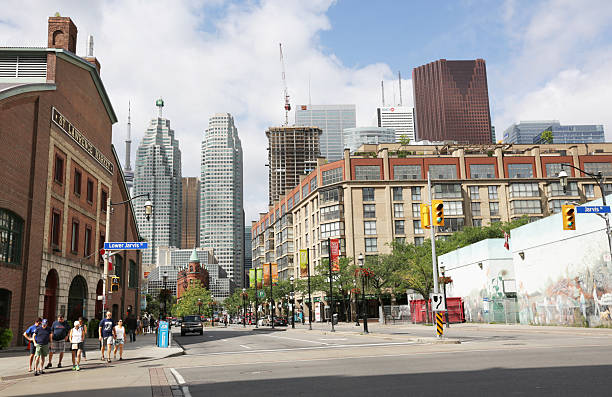 St. Lawrence Neighbourhood, Front Street, Toronto, Canada in Summer Toronto, Canada - August 14, 2016: St. Lawrence Neighbourhood, Front Street, Toronto, Canada in Summer. Historic and modern buildings line Front Street and Wellington at  Jarvis. Pedestrians and traffic around landmarks that include the St. Lawrence Market and the wedge-shaped Flatiron Building, also known as the Gooderham Building. The background shows the  financial district's contemporary bank towers. Condo buildings include mixed-use retail space.  flatiron building toronto stock pictures, royalty-free photos & images