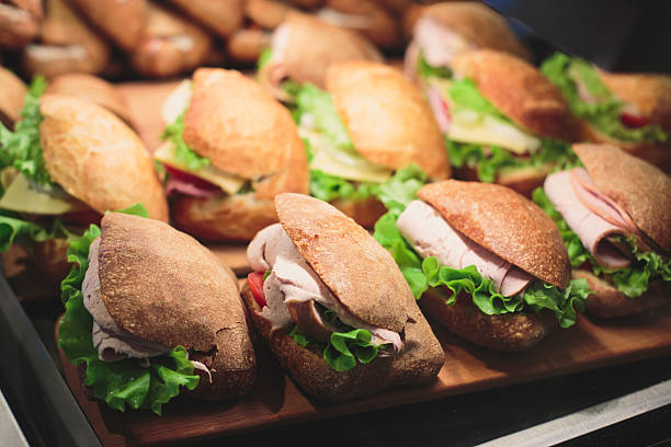 Beautifully decorated catering banquet table with sandwiches Beautifully multicolored decorated catering banquet table sandwiches, sandwich on corporate party event or wedding celebration. delicatessen stock pictures, royalty-free photos & images