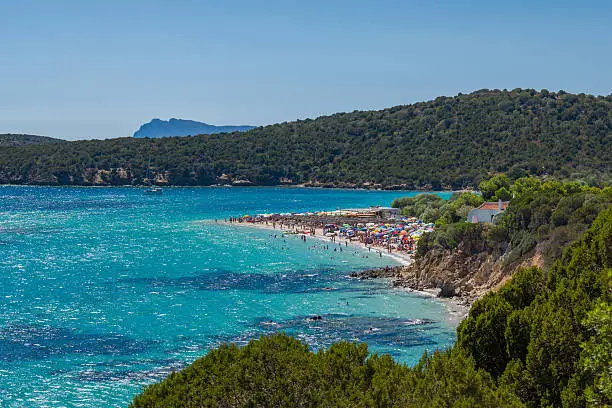 Beautiful beach crowded with tourists and visitors at turquoise blue lagoon in the south of Sardegna Island close to the famous Chia Beach. Spiaggia di Pedralonga - Teulada, South Sardegna, Capo Spartivento, Sardinia.
