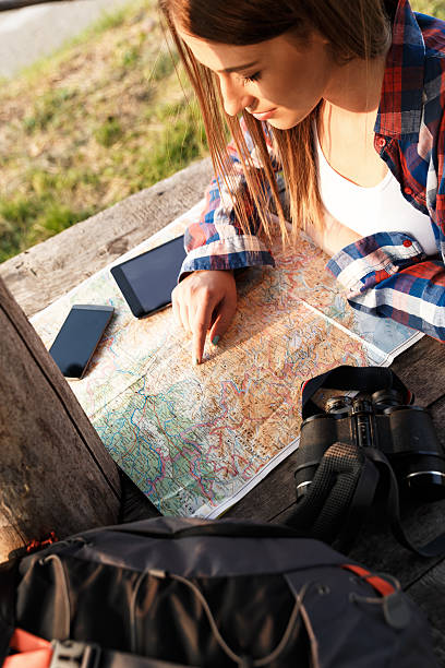 istock Female hiker with backpack reading trekking map 595320804