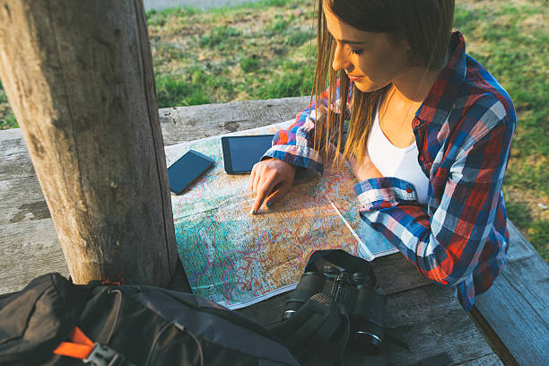 istock Female hiker with backpack reading trekking map 595320924
