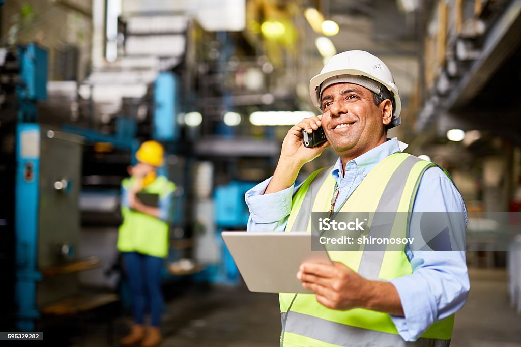 Communicating by radio Smiling worker with radio controlling the work process Latin American and Hispanic Ethnicity Stock Photo