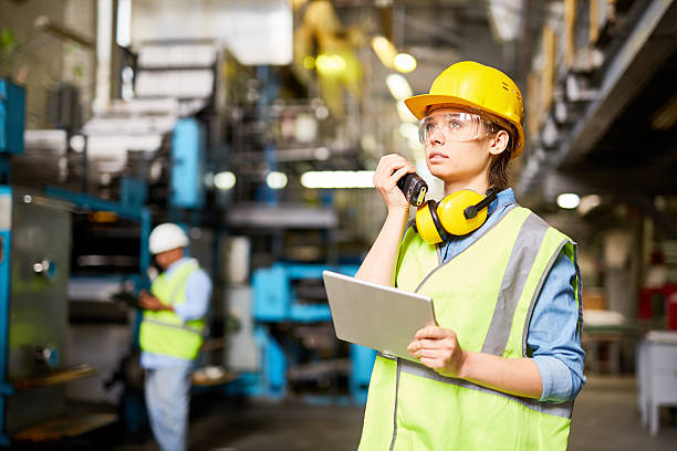 Female engineer at work Young female worker communicating by radio in the factory safety glasses stock pictures, royalty-free photos & images