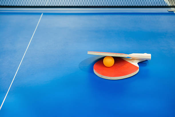 istock pingpong rackets and ball and net on blue pingpong table 595329884