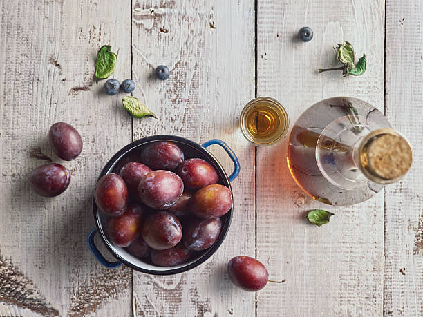 istock Plum brandy (Slivovitz) and fresh plums on white wooden background 595330324
