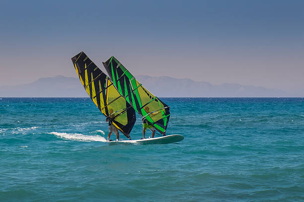 A windsurfer rides across windy turquoise waters on a sunny day in Naxos, Greece, showcasing adventure and summer energy.