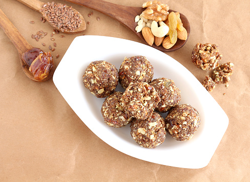 Indian sweet food dry fruits and nuts laddu, which is a traditional, healthy, nutritious and popular dish, is made from items like dates, raisins, almonds, cashew nuts and flaxseeds, in a tray.