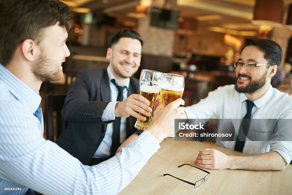 Businessmen celebrating Group of successful businessmen celebrating with glasses of beer Adult Stock Photo