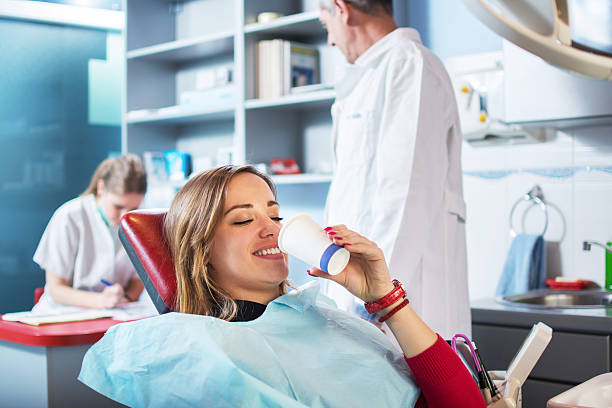 une jeune femme prend un verre d’eau chez le dentiste. - dentist teenager dental hygiene sitting photos et images de collection