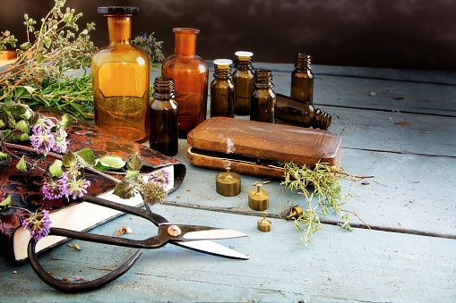 preparing natural medicine, healing herbs, scissors and apothecary bottles on rustic blue painted wood with copy space, vintage style, selected focus