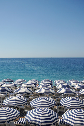 Rows of sun loungers and umbrellas on a beach with calm blue sea