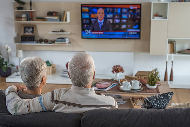 altes paar beobachten fernseher - group of people aging process home interior indoors stock-fotos und bilder